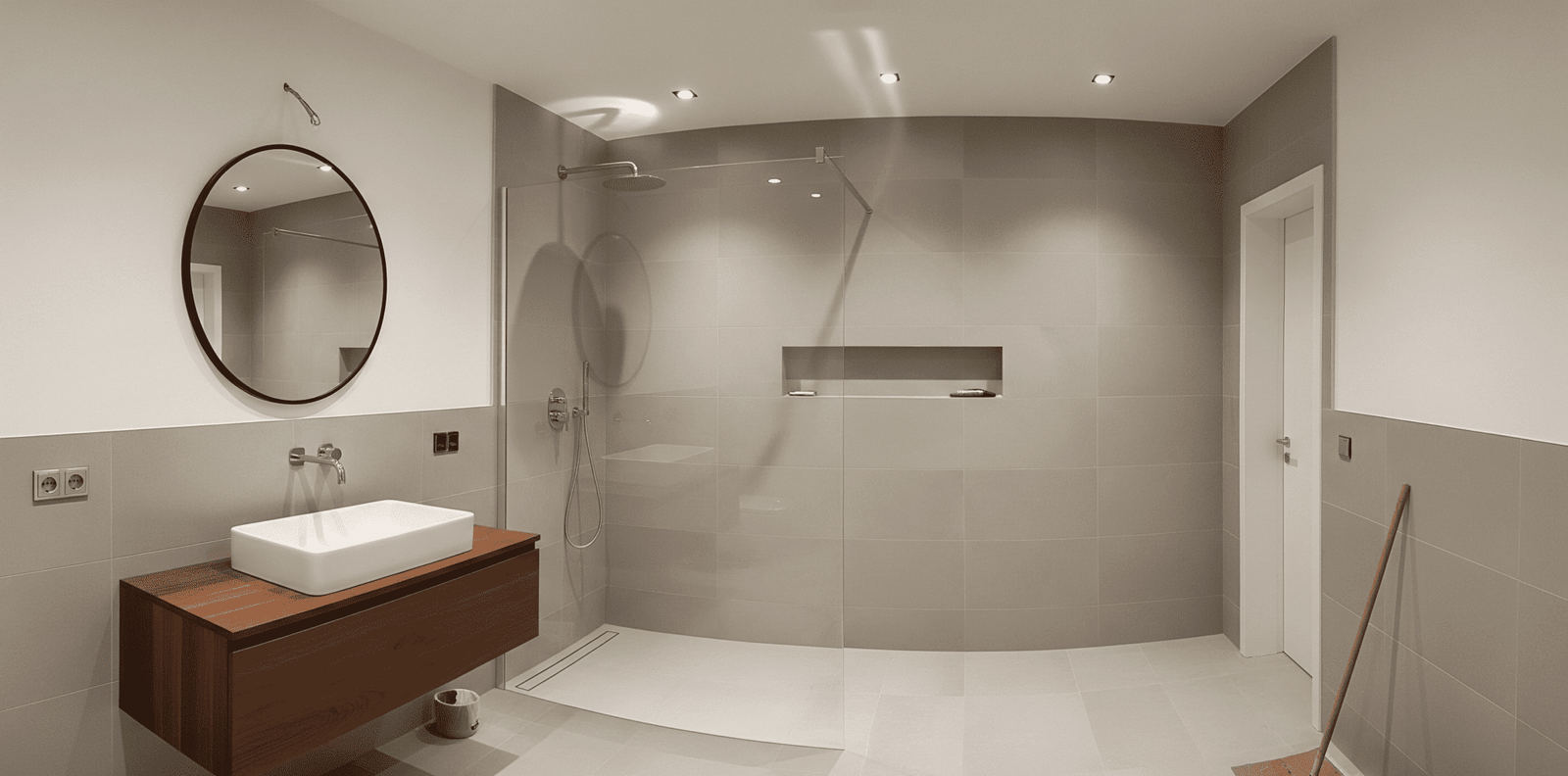 Baño moderno y espacioso resultado de una reforma de baños en Leganés, destacando una ducha a ras de suelo con mampara y un lavabo sobre mueble flotante de madera.