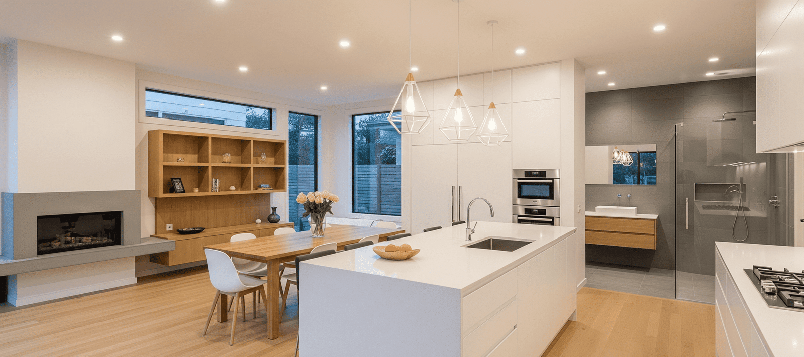 Espacio abierto de diseño moderno en una reforma integral en Leganés, destacando la isla de cocina de cuarzo blanco y el suelo de madera natural.